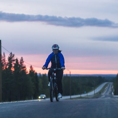 Pyöräilijä pyöräilemässä auringonlaskun aikaan Sallan kevyenliikenteenväylällä